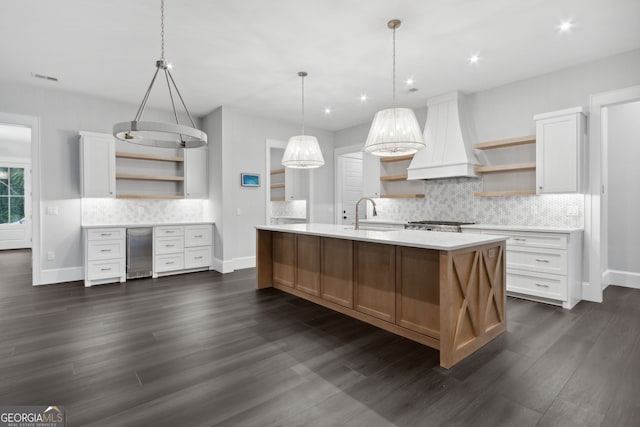 kitchen with hanging light fixtures, decorative backsplash, custom range hood, dark hardwood / wood-style flooring, and white cabinetry