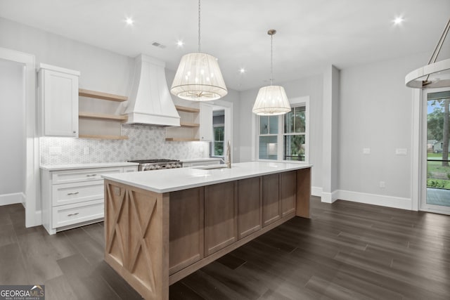 kitchen featuring custom exhaust hood, a center island with sink, sink, dark hardwood / wood-style floors, and white cabinetry