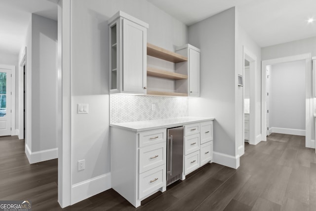 kitchen with tasteful backsplash, white cabinetry, dark hardwood / wood-style flooring, and beverage cooler