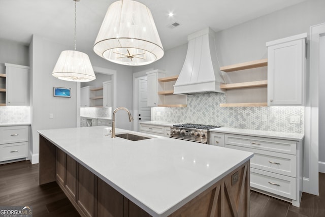 kitchen with high end range, premium range hood, dark wood-type flooring, sink, and white cabinetry