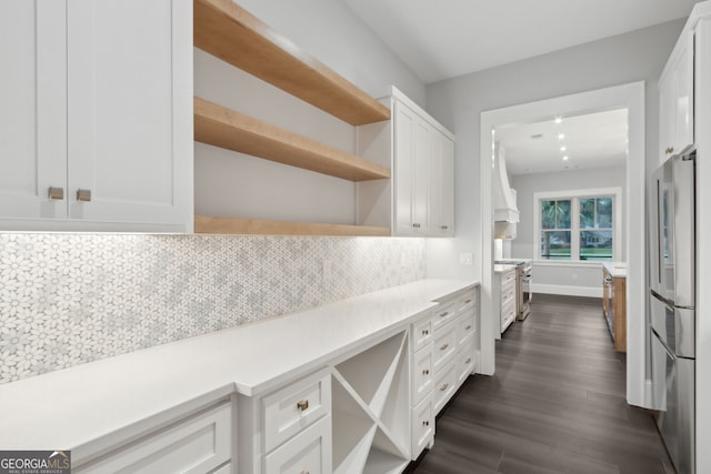 kitchen with white cabinets, dark hardwood / wood-style floors, backsplash, and stainless steel appliances