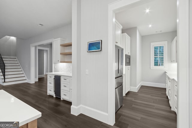 kitchen featuring backsplash, dark wood-type flooring, wine cooler, appliances with stainless steel finishes, and white cabinetry