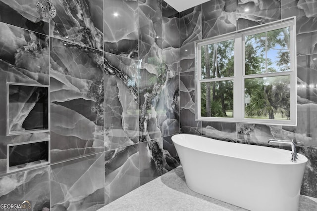 bathroom with a bathtub, plenty of natural light, and tile walls