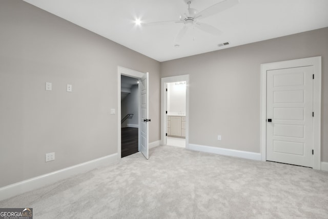 unfurnished bedroom with ceiling fan, light carpet, and connected bathroom