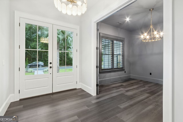 doorway with a notable chandelier, dark wood-type flooring, and french doors