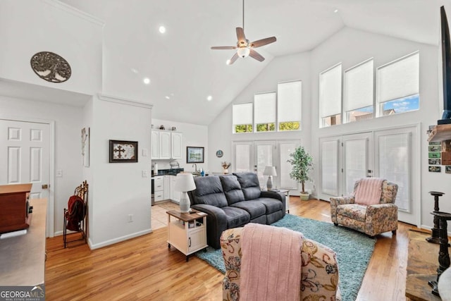 living room with ceiling fan, plenty of natural light, high vaulted ceiling, and light hardwood / wood-style floors