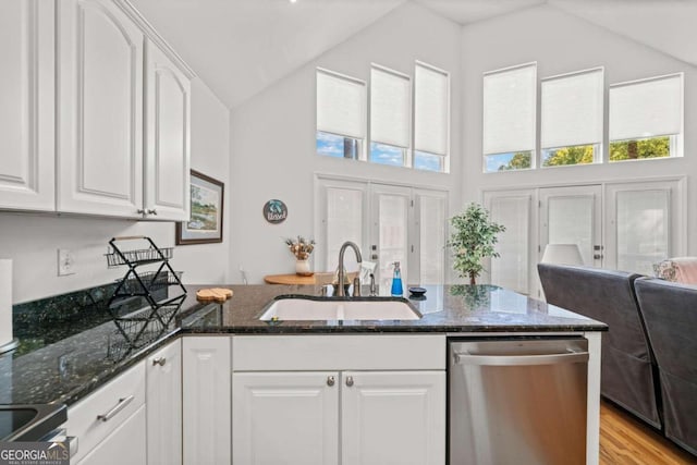 kitchen featuring white cabinetry, sink, stainless steel dishwasher, dark stone countertops, and lofted ceiling