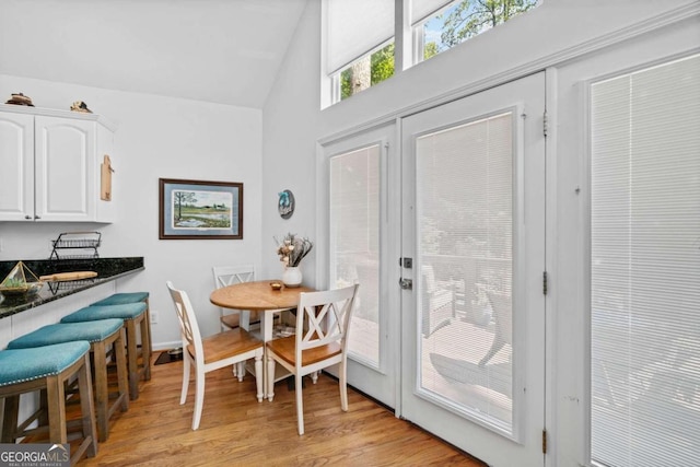 dining room featuring light wood-type flooring and vaulted ceiling