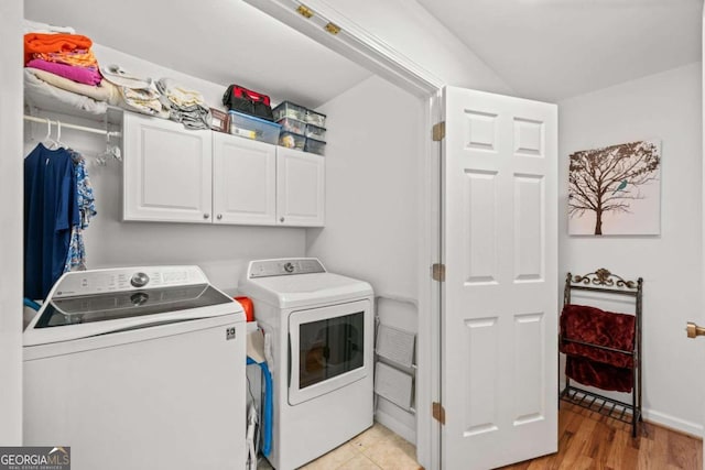 laundry area with cabinets, light wood-type flooring, and separate washer and dryer