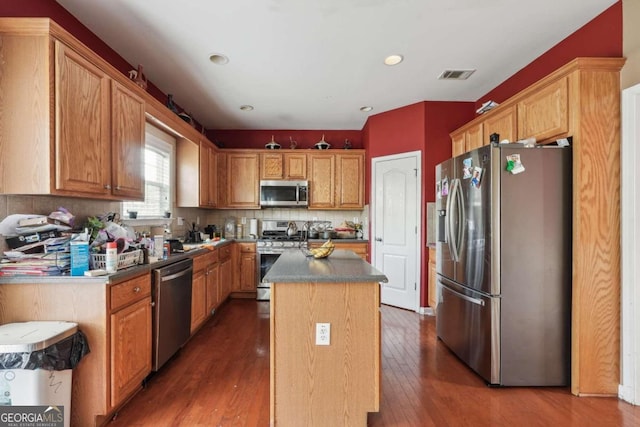 kitchen featuring a kitchen island, stainless steel appliances, hardwood / wood-style floors, and backsplash