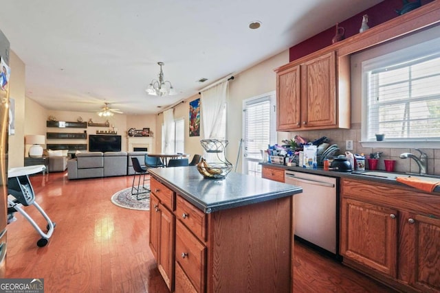 kitchen with dark hardwood / wood-style floors, ceiling fan with notable chandelier, dishwasher, a center island, and decorative backsplash