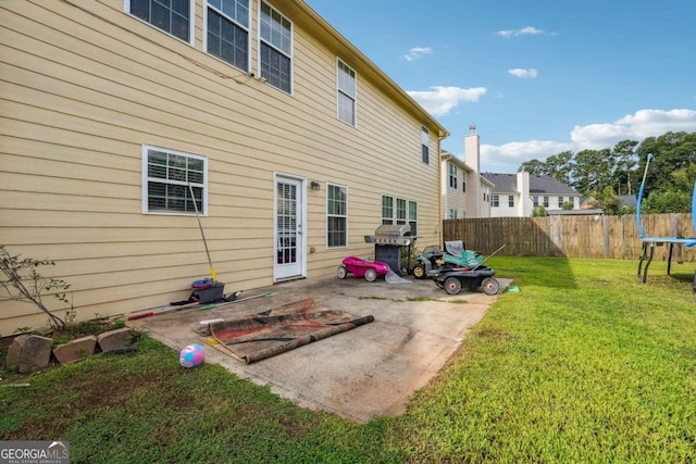 back of property with a patio area, a yard, and a trampoline