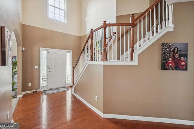 foyer entrance featuring a towering ceiling and hardwood / wood-style flooring