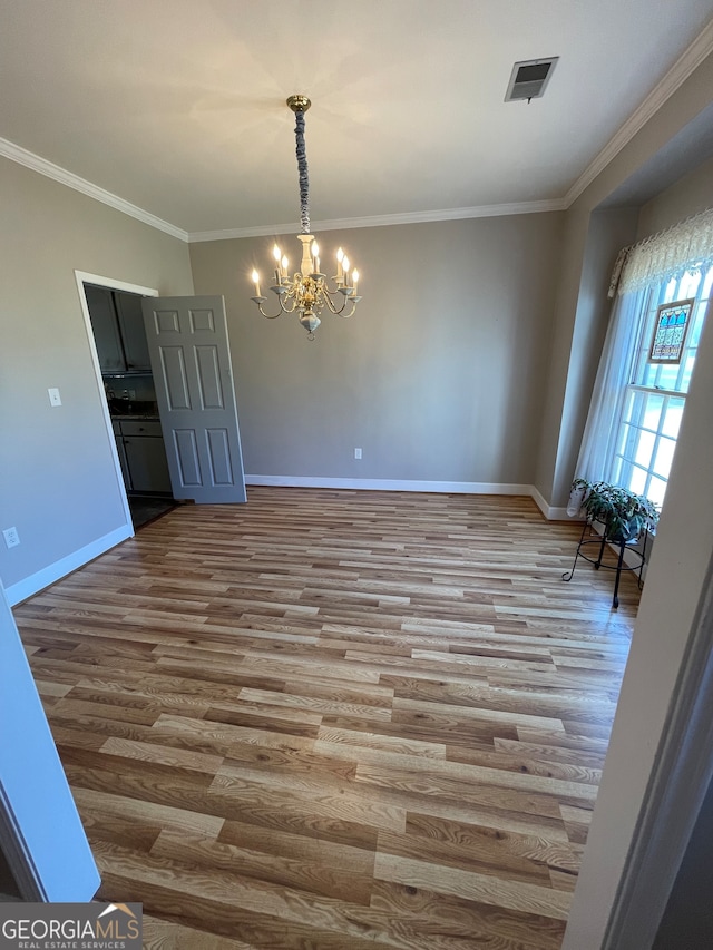 spare room featuring crown molding, a notable chandelier, and wood-type flooring