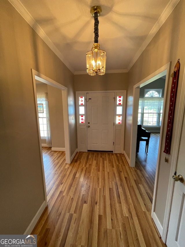 foyer entrance featuring hardwood / wood-style flooring, plenty of natural light, crown molding, and a notable chandelier