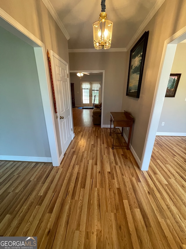 corridor featuring hardwood / wood-style flooring, a notable chandelier, and ornamental molding