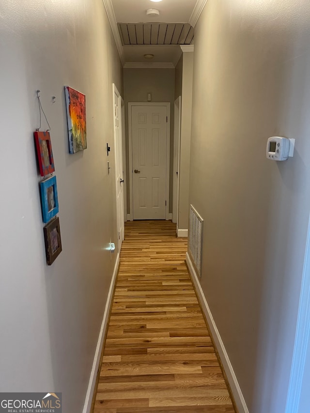 hallway with light hardwood / wood-style floors and ornamental molding