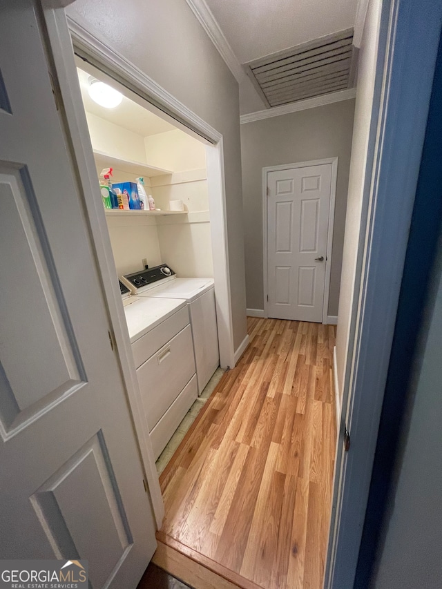 laundry area featuring washing machine and clothes dryer, ornamental molding, and light wood-type flooring