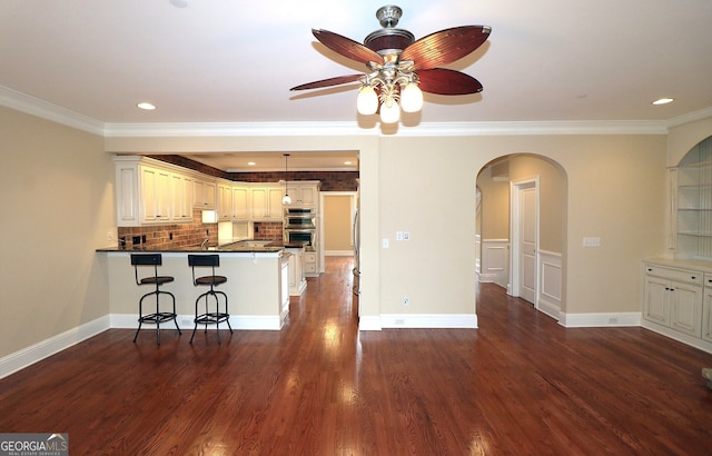 kitchen featuring white cabinets, kitchen peninsula, ornamental molding, and a breakfast bar area