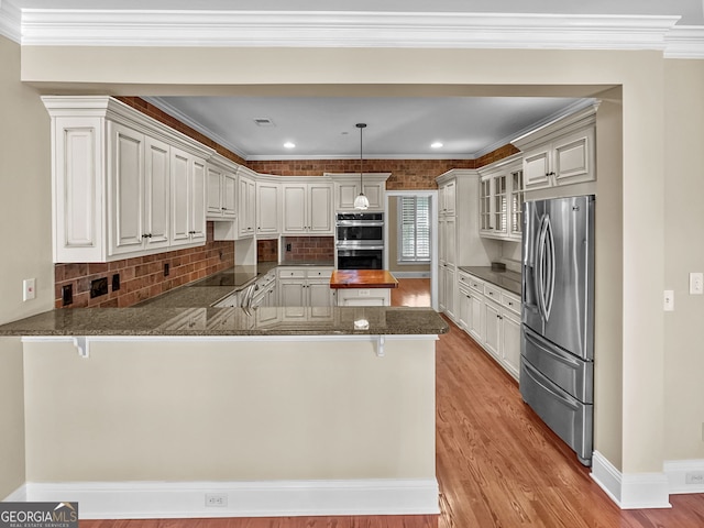 kitchen with kitchen peninsula, appliances with stainless steel finishes, decorative backsplash, and white cabinets