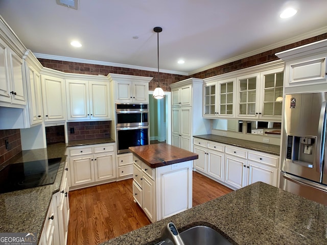 kitchen featuring dark stone countertops, appliances with stainless steel finishes, and hanging light fixtures