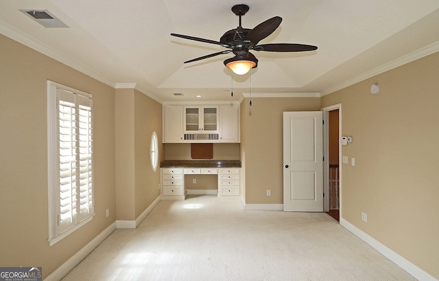 kitchen with crown molding, built in desk, ceiling fan, and white cabinets