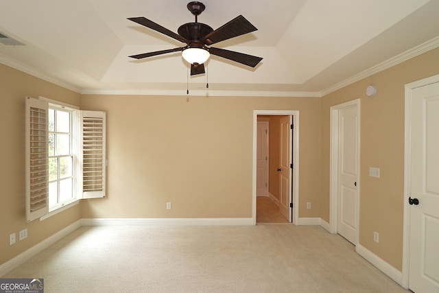 carpeted empty room featuring ornamental molding, lofted ceiling, ceiling fan, and a tray ceiling