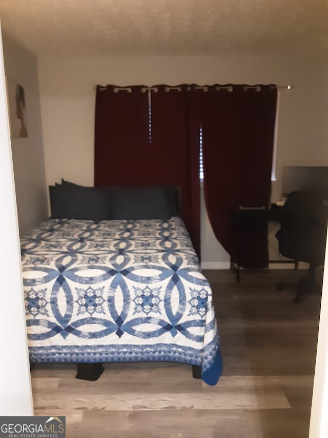 bedroom with hardwood / wood-style floors and a textured ceiling