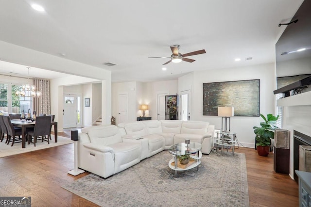 living room with dark wood-type flooring and ceiling fan with notable chandelier