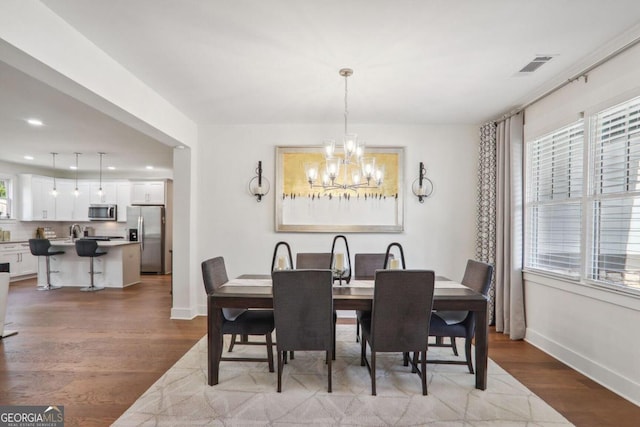 dining space with a notable chandelier, sink, and light hardwood / wood-style floors