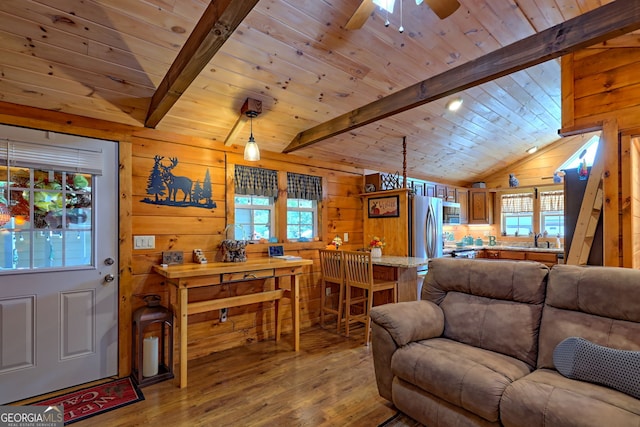 living room featuring light hardwood / wood-style floors, ceiling fan, wood walls, and lofted ceiling with beams