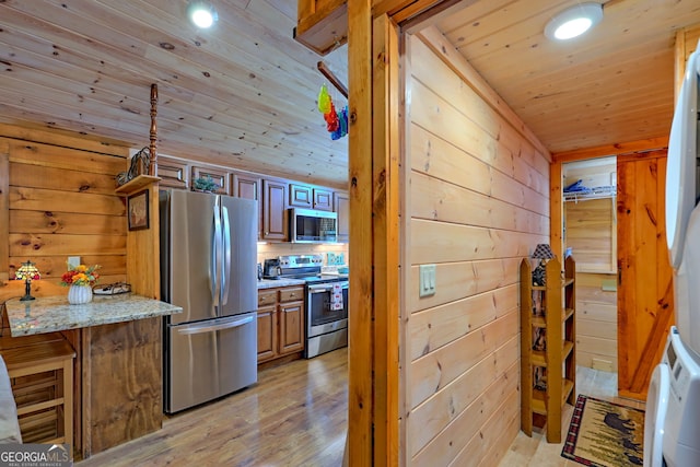 kitchen with wood ceiling, light wood-type flooring, wood walls, and appliances with stainless steel finishes