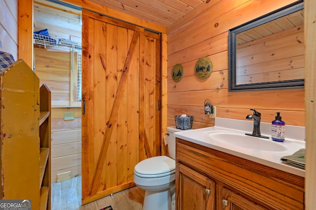 bathroom featuring vanity, toilet, wood walls, and hardwood / wood-style floors