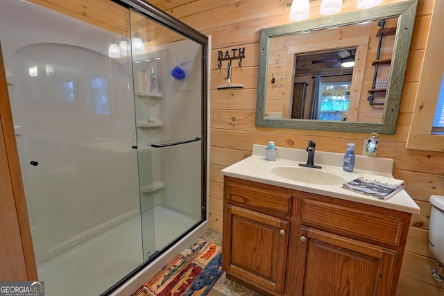 bathroom with vanity, toilet, wooden walls, and a shower with door