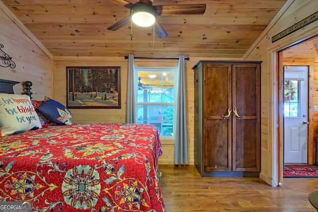 bedroom with vaulted ceiling, multiple windows, and hardwood / wood-style flooring