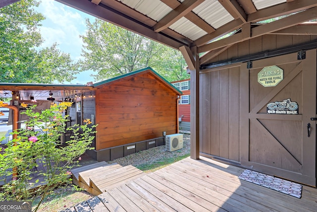 wooden terrace with ac unit and a shed