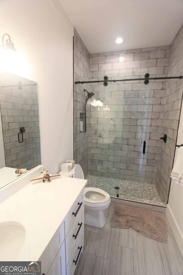 bathroom with vanity, toilet, and a shower with door