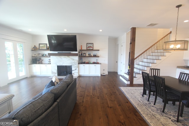 living room with a fireplace, dark hardwood / wood-style flooring, and a notable chandelier