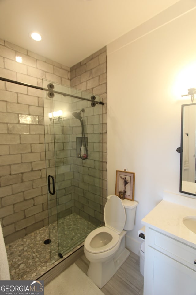 bathroom featuring an enclosed shower, vanity, and toilet