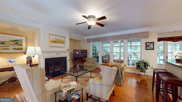 living room with crown molding, wood-type flooring, and ceiling fan