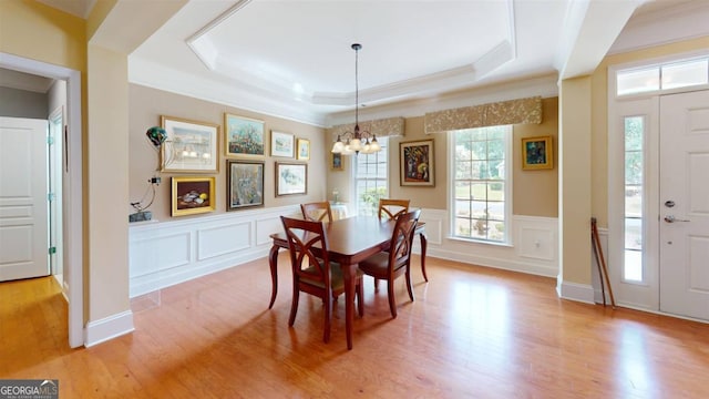 dining room featuring light wood-type flooring, a tray ceiling, a wealth of natural light, and a chandelier