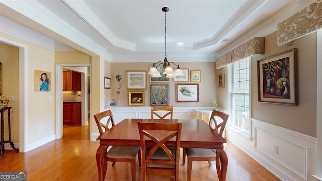 dining room with ornamental molding, hardwood / wood-style flooring, plenty of natural light, and a raised ceiling