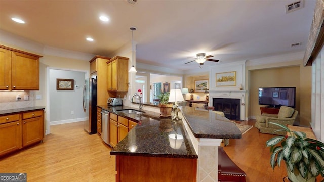 kitchen featuring dark stone counters, light hardwood / wood-style flooring, backsplash, sink, and ceiling fan