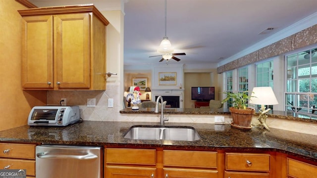 kitchen with stainless steel dishwasher, ceiling fan, sink, and dark stone countertops