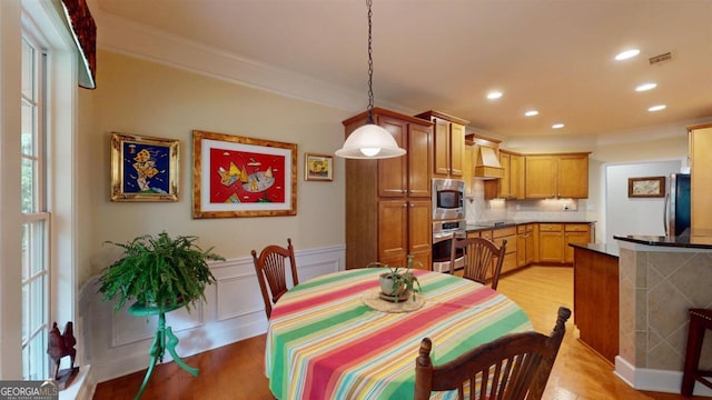 dining room with crown molding and light wood-type flooring