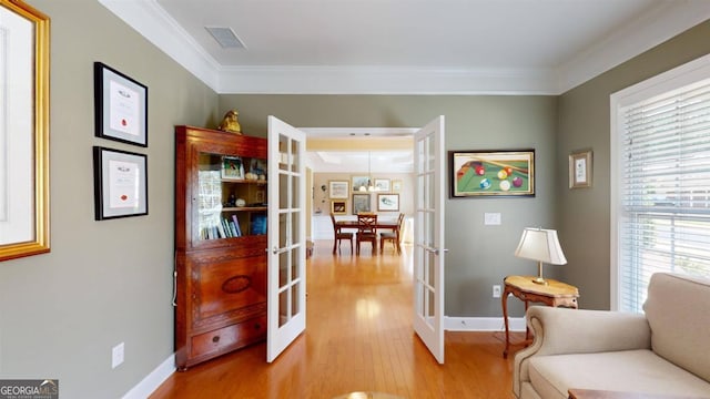 living area featuring ornamental molding, light wood-type flooring, and french doors