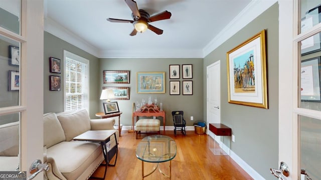 sitting room featuring light wood-type flooring, crown molding, and ceiling fan