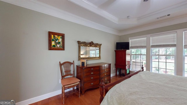 bedroom with crown molding, hardwood / wood-style floors, and a tray ceiling