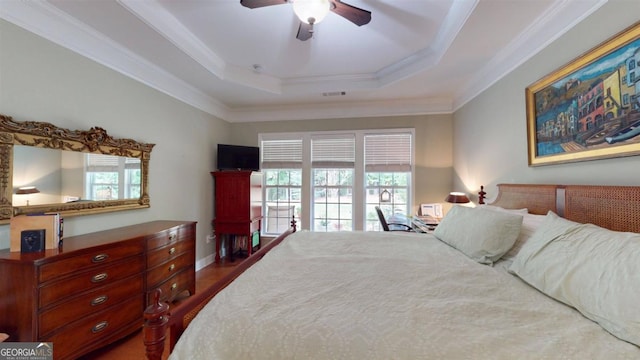 bedroom with multiple windows, ceiling fan, a raised ceiling, and crown molding