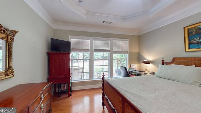 bedroom with a raised ceiling, ornamental molding, and light wood-type flooring